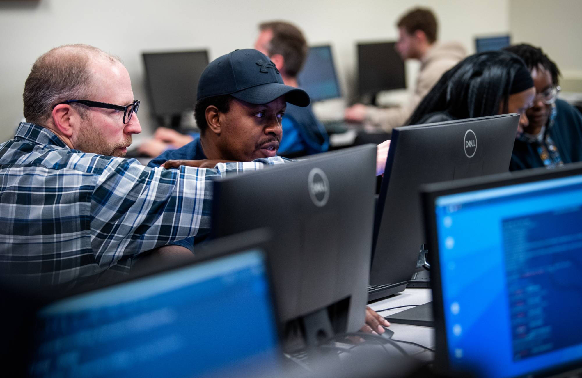 A faculty member assists a student in a computer lab